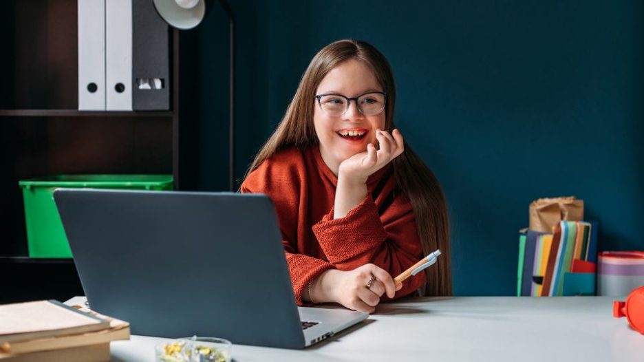 young girl  sitting at table and using laptop at home