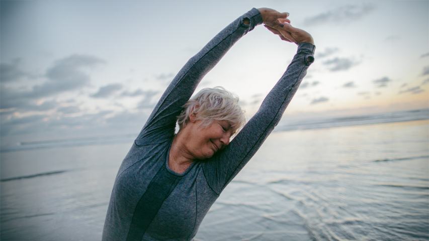 close up of mature lady stretching on beach