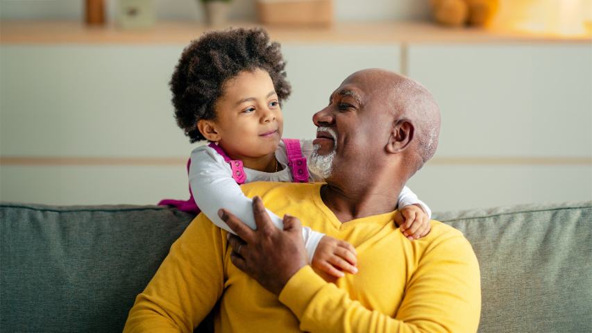 granddad and grand daughter hugging on sofa