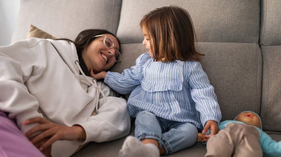 woman and baby girl laughing and playing on sofa