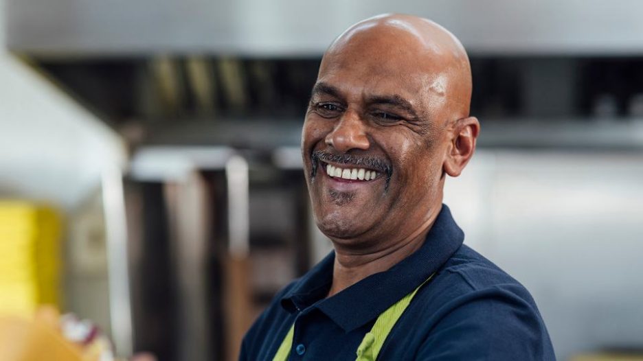 Man running a small takeaway business in North Yorkshire, England. He is preparing food in the kitchen.