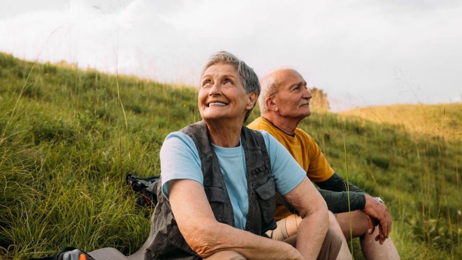 older couple enjoying break from hiking in hills