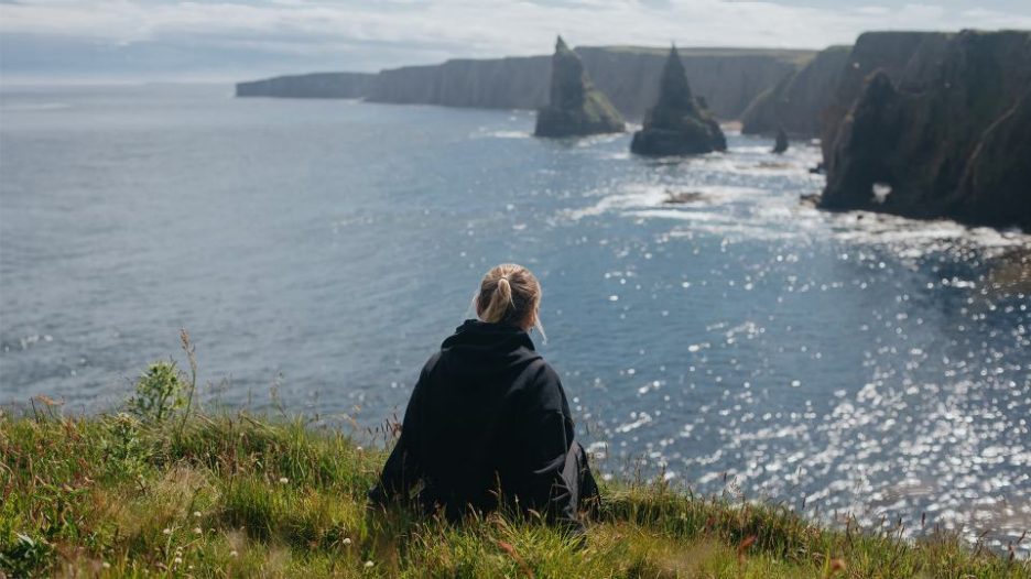 woman sitting on the coast looking at the sea